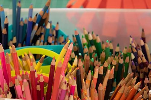 Many bright colored pencils in cups